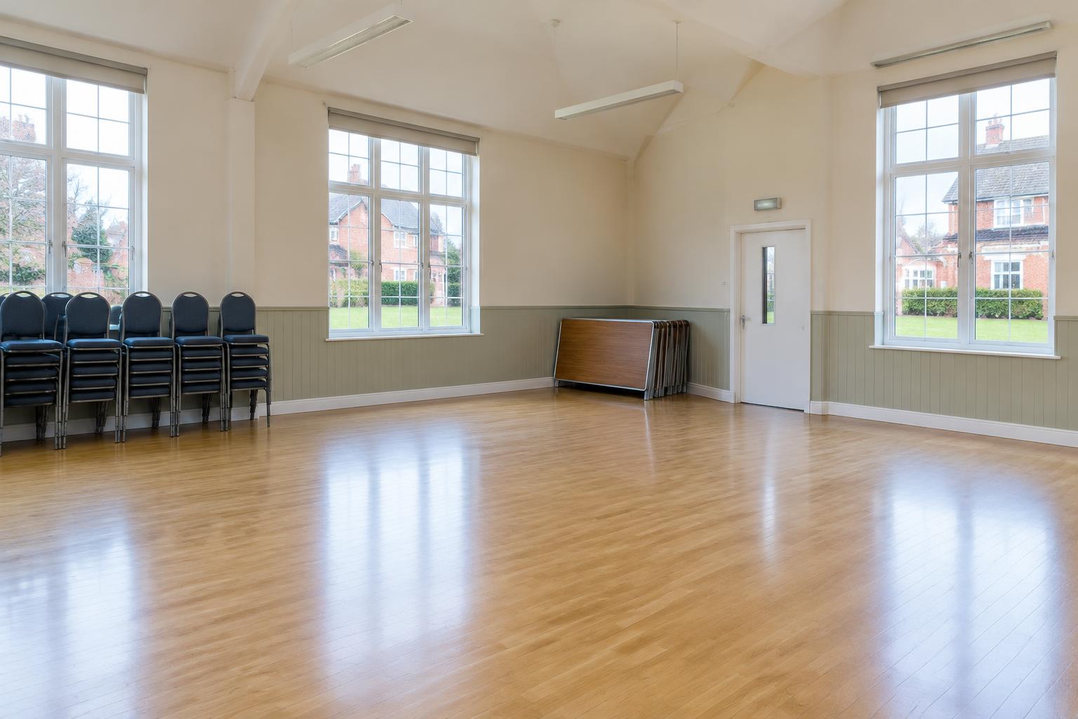AI illustration: clean UK community hall with wooden flooring and stacked chairs